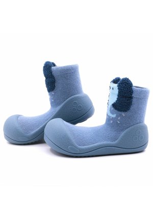 Calcetines para bebés en color azul con suela de goma, que cuentan con una parte superior de tela texturizada y acentos de orejas difusas en un azul más oscuro. Altura hasta la mitad de la pantorrilla.