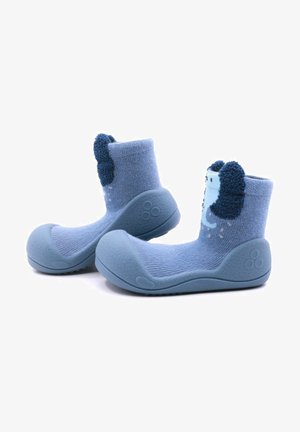 Calcetines para bebés en color azul con suela de goma, que cuentan con una parte superior de tela texturizada y acentos de orejas difusas en un azul más oscuro. Altura hasta la mitad de la pantorrilla.