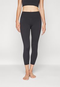 Leggings neri a vita alta realizzati in un materiale liscio ed elastico, di lunghezza cropped. Design aderente con cuciture piatte, senza motivi o dettagli visibili.