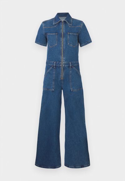 Salopetă din denim cu mâneci scurte, fermoar frontal, două buzunare pe piept și design cu pantaloni largi. Terminată în albastru mediu, cu cusături de contrast.