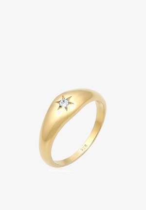 Guldfarvet ring med en glat, rund band og en stjerneformet accent med en enkelt diamant i midten. Stemplet "925."