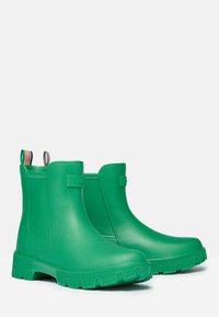 Zelené gumové členkové čižmy s hladkým povrchom, zúženou podrážkou a pruhovanými úchytkami; navrhnuté pre odolnosť voči vode a jednoduché obúvanie.