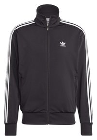 Svart idrottsjacka i polyester, med hög krage, full dragkedja och vita ränder längs ärmarna samt logotyp på bröstet.