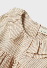 Gestreifte beige Bluse mit einem Rüschkragen, die feine rote Linien aufweist, aus weichem Baumwollmaterial gefertigt ist und dezente Raffungen am Ausschnitt hat.