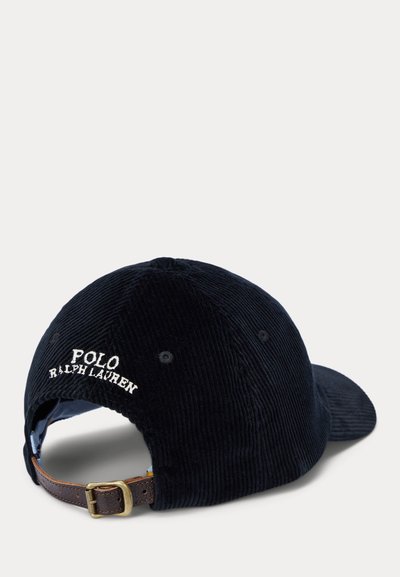 Boné de basebol em corduroy azul marinho com o logótipo bordado "Polo Ralph Lauren". Apresenta uma alça em couro castanho e fivela metálica ajustável.
