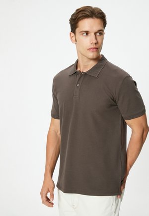 Polo marron avec un col texturé et des manches courtes, doté d'une patte de boutonnage à deux boutons et de fentes latérales pour un ajustement décontracté.