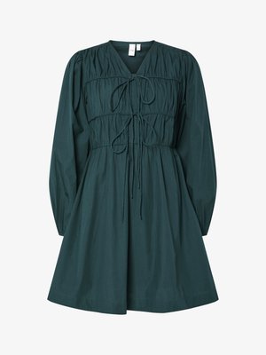 Zaļa kokvilnas kleita ar V veida kakla izgriezumu, pūkainām garajām piedurknēm, saplacinātu ķermeni ar saišu detaļu un izplešanos apakšdaļā. Gluda tekstūra.