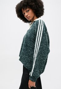 Sweatshirt verde texturizado com detalhes brancos em três faixas, design cropped e colarinho. Feito de material suave e felpudo.