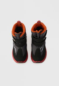 Μαύρα και γκρι αθλητικά παπούτσια με πορτοκαλί λεπτομέρειες, κατασκευασμένα από ένα μείγμα από διχτυωτό υλικό και σουέτ, με ρυθμιζόμενους ιμάντες και υφασμένη κόκκινη σόλα.