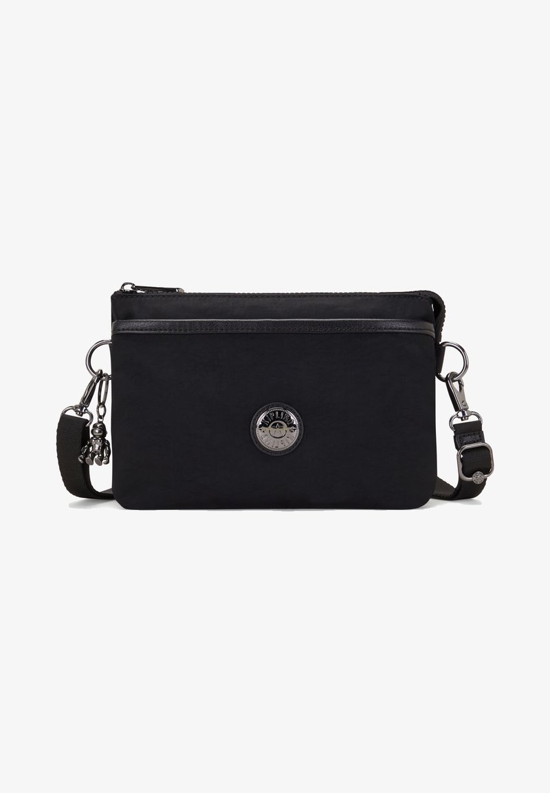 Sort stof crossbody tas har en frontlomme med lynlås, et rundt metallogo og en aftagelig strop med en hardware-charme.