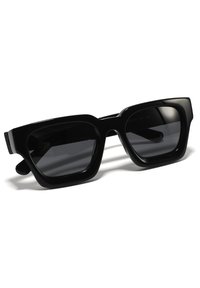 Occhiali da sole neri rettangolari con montatura in plastica spessa e lenti scure, caratterizzati da una forma audace e una finitura lucida.