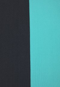 Tri kosa blaga razporejena drug ob drugem: levo v temno črni, v sredini v svetlih teal barvah in desno v temnejših teal barvah. Vsa blaga imajo rebrasto teksturo.