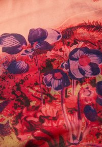Mehrfarbiger Stoff mit floralem Design, tiefen lila Blumen, roten Akzenten und abstrakten Mustern auf einem weichen, strukturierten Hintergrund.