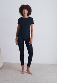 Black short-sleeve top and fitted leggings, both made of a smooth, stretchy fabric. The outfit features a minimalist design with no patterns.
