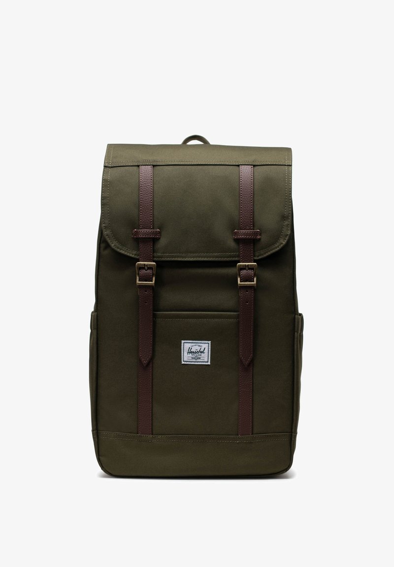 Grüner Stoff-Rucksack mit braunen Lederträgern, zwei vorderen Schnallen, einem oberen Klappenverschluss und einer kleinen Vordertasche mit einem Logopatch.