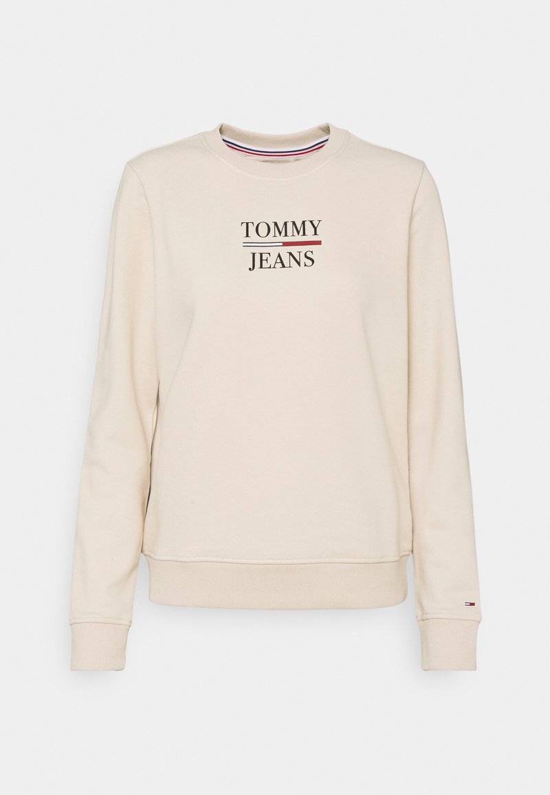 Beige crewneck sweatshirt med "TOMMY JEANS" broderat på framsidan, långa ärmar och en liten Tommy Hilfiger-flagglogga på vänster mudd.