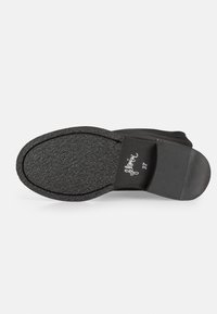Semelle noire de botte avec une surface texturée, un bout arrondi et un léger talon ; arbore un logo et des bords lisses pour une finition sans couture.