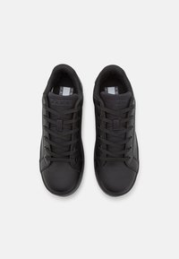 Černé sportovní boty s hladkým koženým svrškem a síťovinovými prvky. Obsahují kulaté tkaničky, plochou gumovou podrážku a minimalistický design.