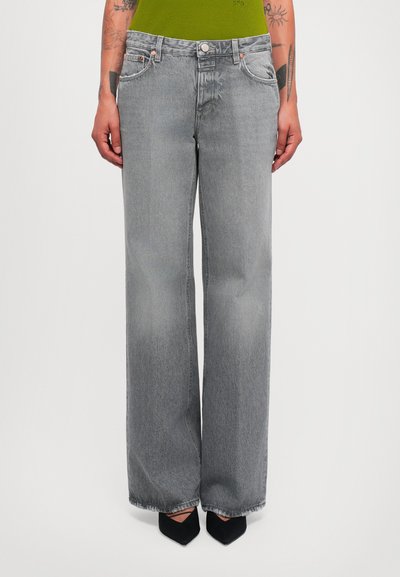 Gray wide-leg jeans with a high waist, faded texture, subtle distressing, and copper hardware; worn with black pointed heels.