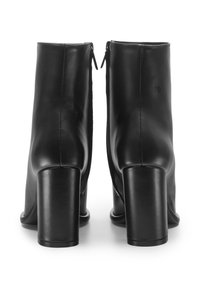 Stivali neri in pelle fino alla caviglia con tacco a blocco alto, texture liscia, dettagli con cucitura verticale e cerniere posteriori.
