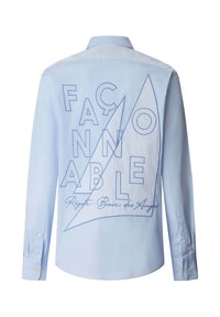 Lichtblauw overhemd met lange mouwen en een kraag, met grote omrande letters en een ontwerp van een zeilboot op de achterkant, met de tekst "FAÇONNABLE."