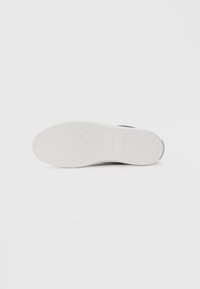 Fehér sportcipő talp, amely textúrázott tapadási mintával és Calvin Klein márkajelzéssel rendelkezik; ívelt forma és sima felület.