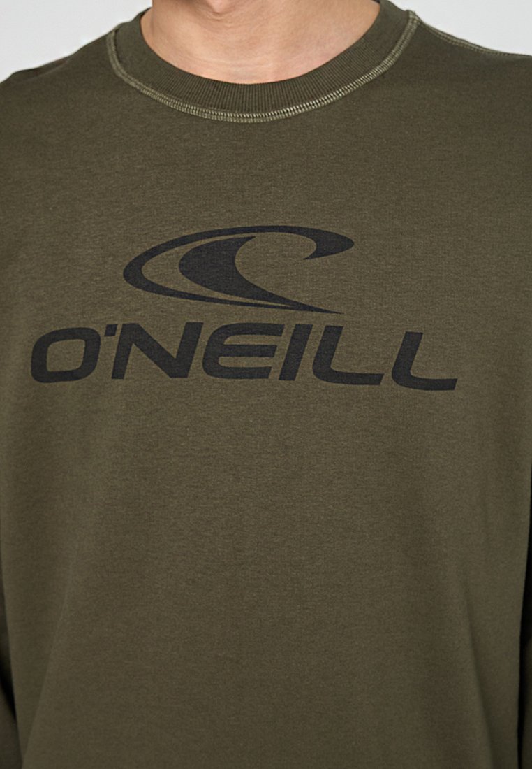 Nahaufnahme einer Person, die ein olivgrünes Shirt mit einem schwarzen O'Neill-Logo und einer Wellen-Grafik auf der Brust trägt.