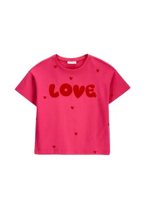 Jasnoróżowa koszulka z krótkim rękawem z dużym czerwonym tekstem "LOVE" i małymi czerwonymi sercami rozsianymi po tkaninie.
