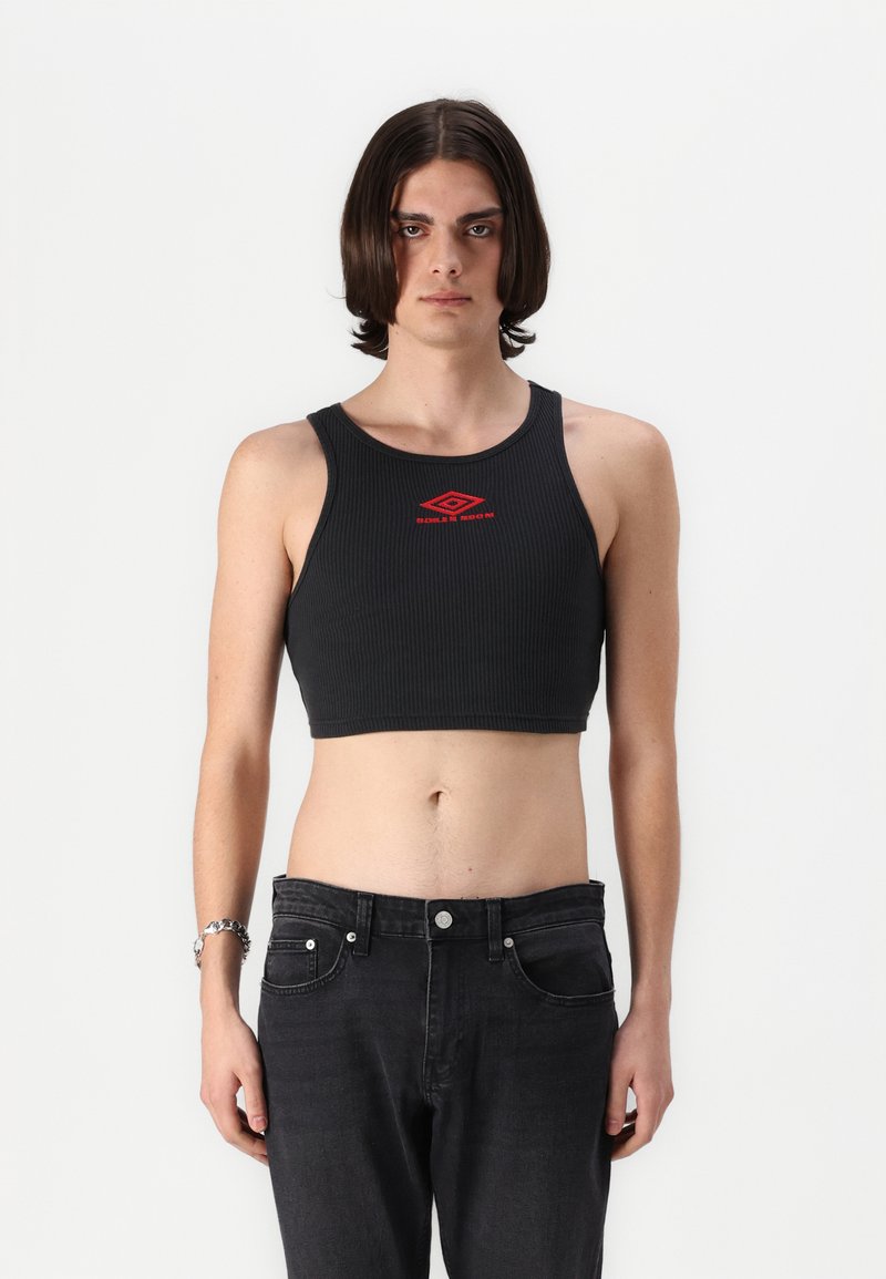 Black ribbed crop top with a round neckline and red logo detail, paired with high-waisted black jeans. Smooth texture, fitted design.