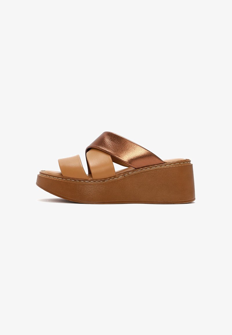 Sandales compensées marron avec des lanières croisées en cuir métallique cuivre et en cuir matte tan. Présente une semelle épaisse et texturée avec des coutures contrastées.