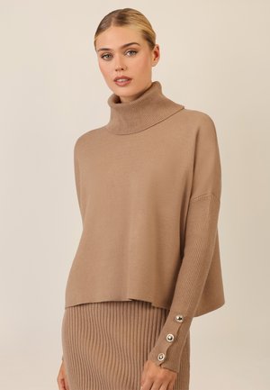 Beiger Strickpullover mit hohem Kragen, ausgestattet mit gerippten Ärmeln und dekorativen Knöpfen an den Bündchen. Weicher Stoff und lockere Passform.