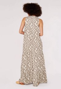 Robe maxi avec un motif géométrique en beige et marron clair. Confectionnée en tissu léger avec des volants à étages et un design sans manches.