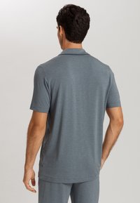 Pánská polokošile s krátkým rukávem v melírované šedé látce. Má klasický límec a uvolněný střih, s hladkou texturou a jemným leskem.