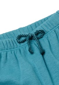 Tyrkysový elastický pás se šňůrkou se třásněmi. Měkká tkanina s hladkým povrchem, vykazující jemné nařasení v pase.