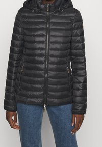 Czarna pikowana kurtka puchowa z zamkiem błyskawicznym, elastycznymi mankietami i odpinanym kapturem. Posiada poziome przeszycia i zapinane na zamek boczne kieszenie.