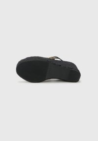 Ciabatte flip-flop nere con upper in tessuto intrecciato testurizzato, suola in gomma piatta e un sottile accento intrecciato sul piede.