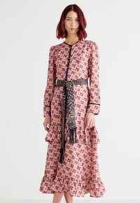 Μακρύ φόρεμα με λουλουδάτο σχέδιο σε ροζ χρώμα με μαύρες λεπτομέρειες. Διαθέτει βολάν στο στρίφωμα και μακριά μανίκια, με ζώνη σε λεοπάρ σχέδιο στη μέση.