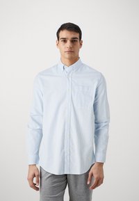 Camisa de botonadura azul claro y blanca a rayas, de mangas largas, con un bolsillo en el pecho, hecha de una tela suave, con un cuello clásico.