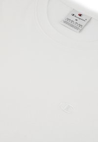 Weißes Baumwoll-T-Shirt mit Rundhalsausschnitt und kurzen Ärmeln, mit einem dezenten, weißen gestickten Logo auf der linken Brustseite.