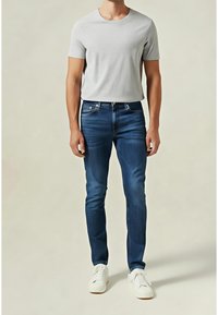 Grå kortärmad t-shirt i slim fit, matchad med blå jeans. Vita sneakers fulländar-outfitten. Enkelt och rent design.