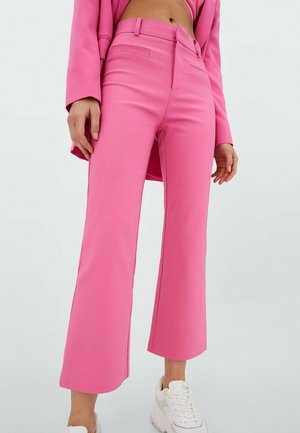 Pantalon rose sur mesure avec une taille haute, un devant plat et des jambes larges. Comprend des poches latérales et un tissu lisse et texturé.