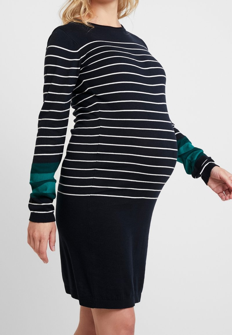 Těhotenské šaty v námořnické modři s bílými vodorovnými pruhy. Dlouhé rukávy mají tyrkysový akcent. Měkká pletenina. Přiléhavé kolem pupku.