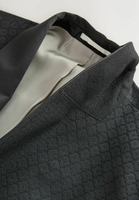 Klassikaline must tekstiiljakki krae, millel on sile helebeez vooder ja nähtavad õmblused.