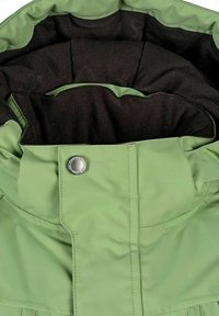 Grön jacka med krage och svart innerfoder samt stängning med metallknapp som har varumärkestext.