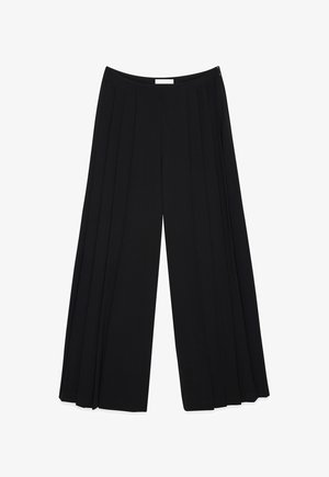 Mustat löysät housut, joissa on laskokset. Sileä kangas, korkea vyötärö ja sivuvetoketjukiinnitys. Kevyt ja virtaava muotoilu.