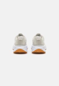 Neutralne sneakersy z gładką, jasnoszaro zamszową cholewką, siateczkowymi detalami, białą podeszwą środkową i kontrastującą pomarańczową gumową podeszwą zewnętrzną.