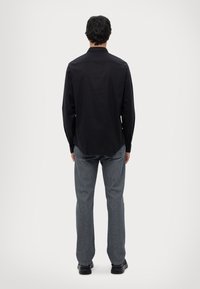 Zwarte lange mouwen shirt met een spitse kraag, van katoen en met een normale pasvorm. Gecombineerd met recht gesneden grijze jeans en zwarte schoenen.
