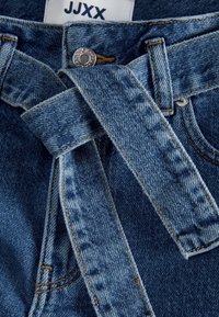 Denim trousers with a light blue wash, featuring a belted waist and visible stitching details. Includes a silver button and classic pockets.