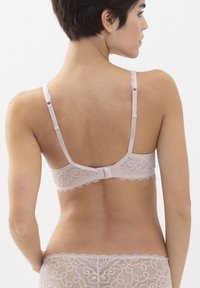 Pitkänmallinen pehmeä beigenvärinen pitsi-rintaliivi, jossa on aaltoilevat reunat, säädettävät olkaimet ja hakas- ja silmukkakiinnitys. Ominaisuuksiin kuuluu monimutkainen kukkakuvio.