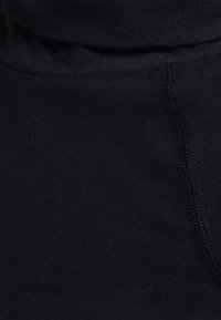 Tela negra con una textura suave, que presenta un cuello alto y costuras visibles en un tono ligeramente más oscuro.